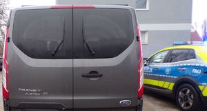 Szare auto, w tle policyjny radiowóz.