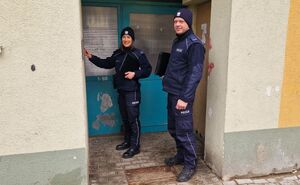 Dzielnicowi stoją przy drzwiach wejściowych do budynku.