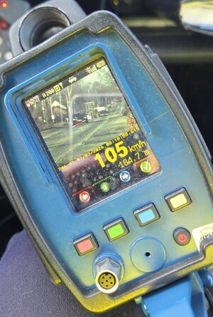 Ręczny miernik prędkości, na którym widać samochód jadący z prędkością 105 km/h.