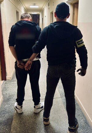 Kryminalny stoi z zatrzymanym mężczyzną.