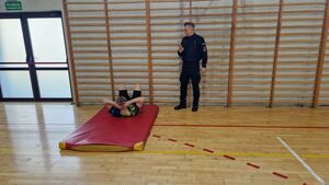 Zawodnik wykonuje tak zwane brzuszki na materacu, czynności przygląda się policjant.