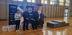 Uczeń rzuca piłką lekarską, czynności przygląda się policjant.