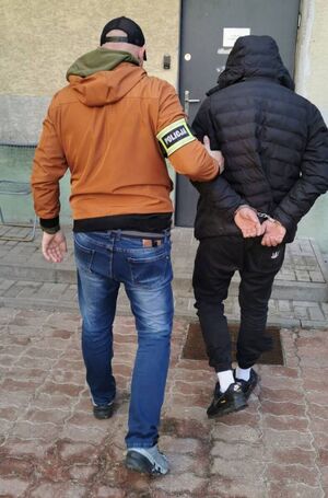 Nieumundurowany policjant wchodzi do komendy z zatrzymanym mężczyzną