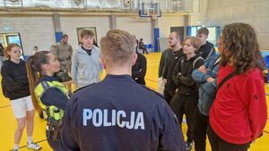 Uczniowie zgromadzeniu przy stoisku policjantki z Wydziału Ruchu Drogowego Komendy Powiatowej Policji w Pabianicach.