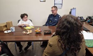 Chłopiec siedzi obok Komendanta Powiatowego Policji w Pabianicach.