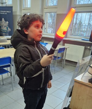 Chłopiec stoi z latarką.