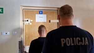 Policjant stoi z zatrzymanym mężczyzną.