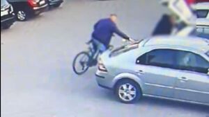 Mężczyzna na rowerze sięgający po cudzą torbę.