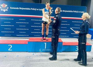 Zawodniczka odbierająca puchar z rąk Komendanta. Obok policjantka.