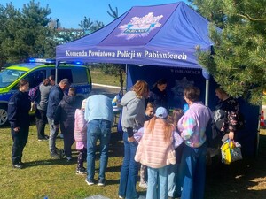 Stanowisko profilaktyczne, na którym widać policjantów, radiowóz oraz granatowy namiot, pod którym są uczestnicy wydarzenia.