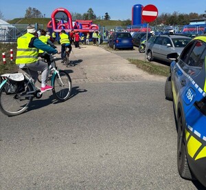 Uczestnicy rajdu wjeżdżający na teren stacji uzdatniania wody, w tle policyjny radiowóz.
