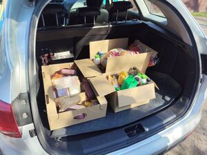 Wnętrze bagażnika pojazdu, w którym znajdują się kartony z jedzeniem.