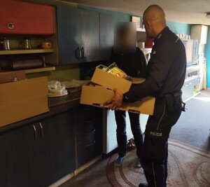 Policjant w mieszkaniu przekazujący jedzenie.