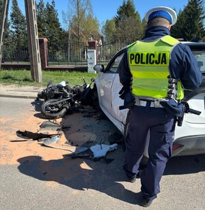 Policjant wykonujący oględziny uszkodzonych pojazdów.