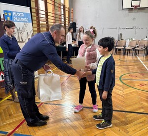 Zastępca Komendanta Powiatowego Policji w Pabianicach gratulujący laureatowi konkursu.