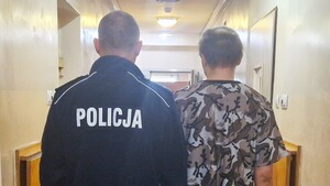 Policjant stoi z zatrzymanym mężczyzną.