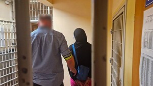 Nieumundurowany policjant stoi z zatrzymaną kobietą.