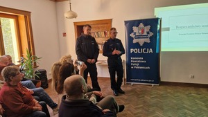 Komendant Powiatowy Policji w Pabianicach przemawia do seniorów, obok szefa pabianickich stróżów prawa stoi dzielnicowy z Posterunku Policji w Hermanowie.