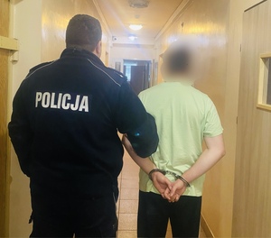 policjant stojący z zatrzymanym mężczyzną