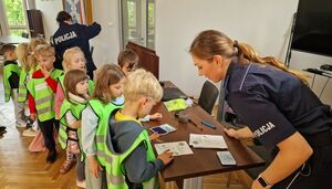 Policjantka odbijająca linie papilarne palców dzieci.