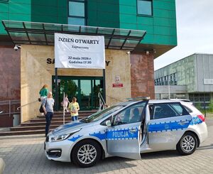 Policyjny radiowóz przed budynkiem sądu.