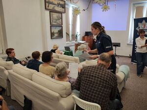 Policjantka wręcza seniorom ankiety.