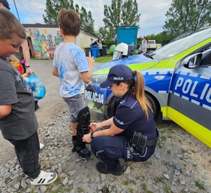 Policjantka zakłada chłopcu sprzęt służbowy.