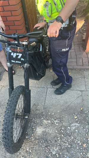 policjant trzymający motocykl elektryczny.