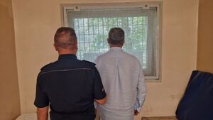 Umundurowany policjant sto z zatrzymanym mężczyzną.