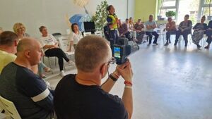Uczestnik spotkania trzyma rękach miernik prędkości.
