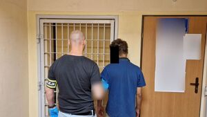 Nieumundurowany policjant stoi z zatrzymanym mężczyzną.