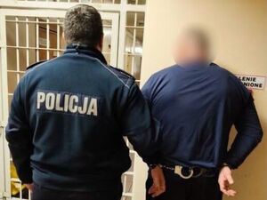 Umundurowany policjant stoi z zatrzymanym mężczyzną.