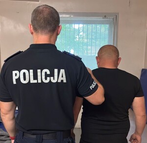 umundurowany policjant trzyma zatrzymanego