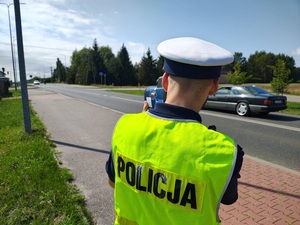 umundurowany policjant w kamizelce odblaskowej dokonuje pomiaru prędkości