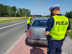 umundurowani funkcjonariusze kontrolują samochód osobowy