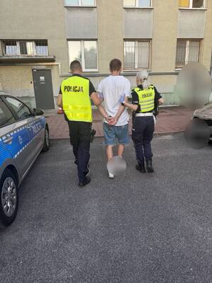 umundurowani funkcjonariusze prowadzą zatrzymanego