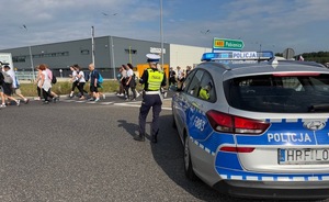 umundurowana policjantka stoi przy radiowozie i zabezpiecza pielgrzymkę