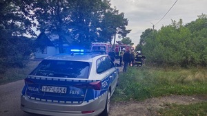 policyjny radiowóz stoi przy karetce w te widać strażaków oraz wozy strażackie