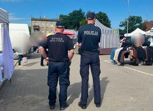 funkcjonariusz policji wraz z strażnikiem miejskim kontrolują targowiska przeciw kieszonkowcom