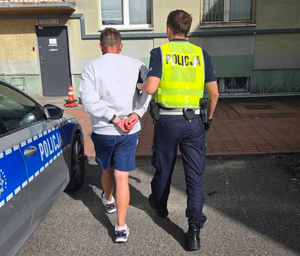 umundurowany policjant prowadzi zatrzymanego