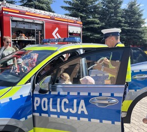 Dzieci i policjant przy radiowozie.