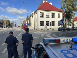 dwóch policjantów stojących tyłem przy skrzyżowaniu