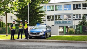 trzech policjantów ruchu drogowego stojący przy radiowozie