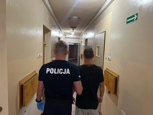 umundurowany funkcjonariusz prowadzi zatrzymanego