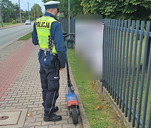 umundurowany policjant wykonujący czynności przy hulajnodze elektrycznej