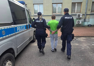 umundurowani policjanci prowadzą zatrzymanego