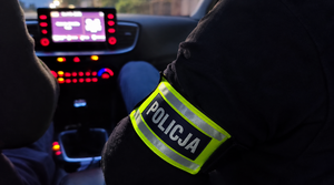 nieumundurowani funkcjonariusze z opaską na ręce z napisem Policja podczas jazdy radiowozem nieoznakowanym