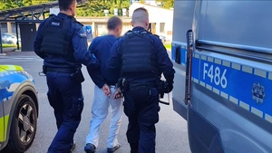 umundurowani funkcjonariusze prowadzą zatrzymanego