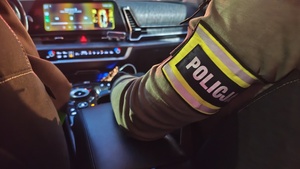 nieumundurowani policjanci z opaską z napisem Policja w wewnątrz radiowozu