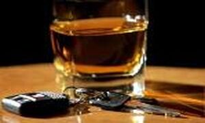 stojąca na stole szklanka z alkoholem i obok leżące kluczyki